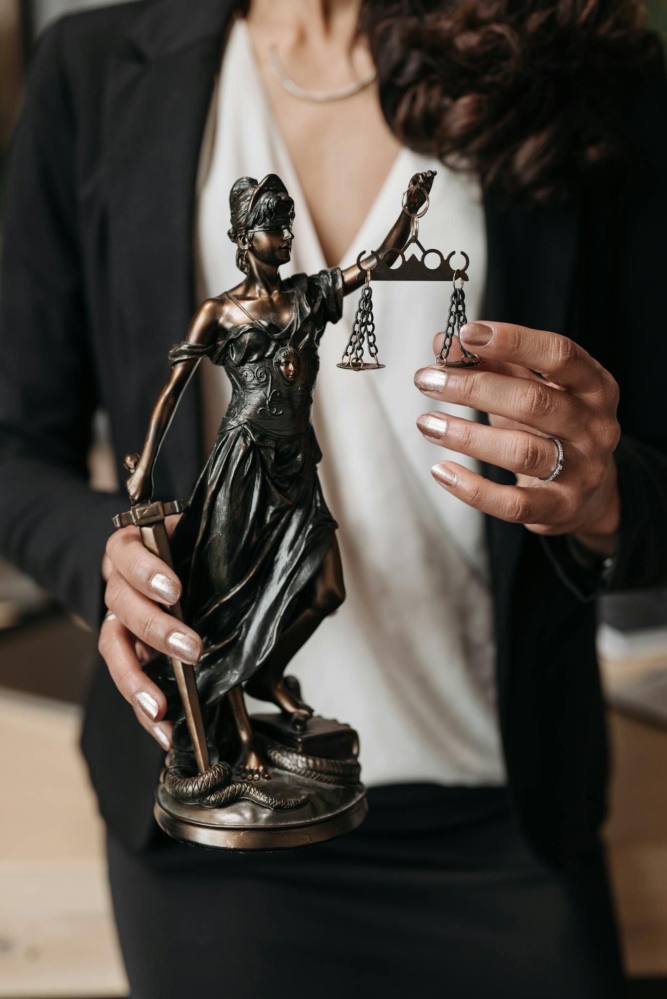 Close-up of Lady Justice statuette held by a lawyer, symbolizing law and justice.